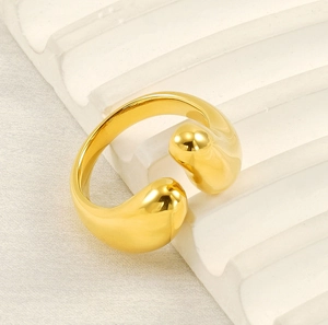 Detailed view of an 18K gold plated adjustable open ring with bulbous ends on a wavy stand