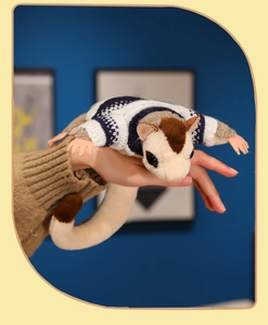 Detail of sugar glider plush wearing a blue striped sweater held in hand