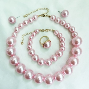 Flat lay of pink pearl jewelry set featuring necklace, bracelet, earrings and golden ring