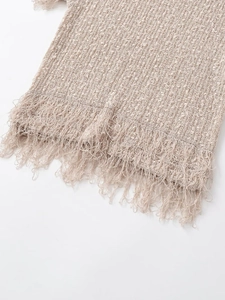 Detailed macro view of beige knit vest featuring premium tassel fringe and woven texture