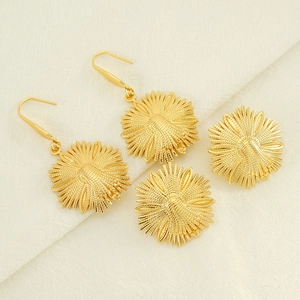 Détail de boucles d'oreilles fleur dorée avec pétales texturés et finition métallique