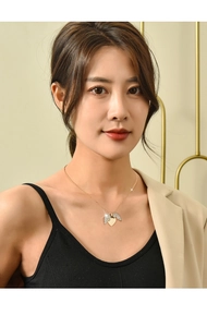 Close-up of golden titanium heart necklace with winged pendants on a female model