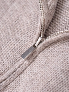 Detailed macro view of beige knit wool fabric texture and high-quality silver metal zipper
