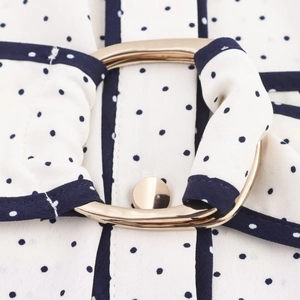 Détail de la robe chemise à pois bleu marine avec boucle dorée et tissu blanc premium