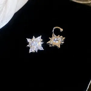 Silver star starburst earrings with sparkling zircon stones on black velvet background