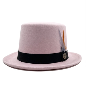 Detail view of pink wool top hat with black ribbon, feather and vintage metal badge