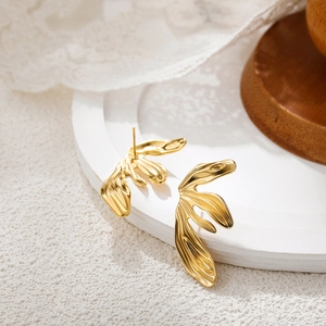 Macro shot of gold organic wave earrings on white lace and wood background details