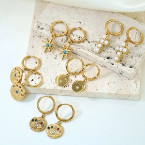 Detail of gold hoop earrings with star, devil eye and I love you engraved charms