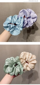Close-up of four pleated satin scrunchies in blue purple and champagne with metallic luster
