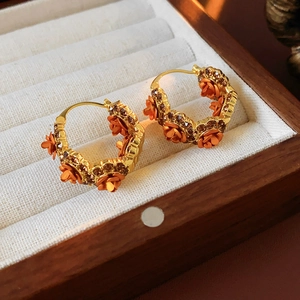 Close-up of gold-plated flower earrings with orange petals in a jewelry gift box