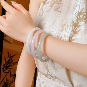 Detailed view of translucent jade bangles in white, purple, and green on a wrist