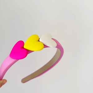 Detailed view of sweet pink sponge headband with colorful pink yellow and white 3D hearts