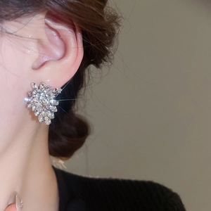Close-up of sparkling leaf-shaped crystal stud earrings worn by a model in warm light