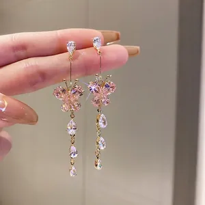 Macro view of crystal butterfly tassel earrings with sparkling pink wings and long zircon drops