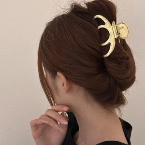 Golden metal hair claw clip for thick hair shown from a side view on female model