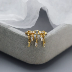 Macro shot of gold chain ring with rectangular zircon tassels on gray velvet background