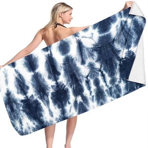 Detail view of a navy blue tie-dye microfiber beach towel held by a model on white background