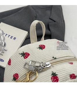 Detail of strawberry pattern corduroy backpack with durable handle and gold zippers