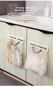 Detail of hanging mesh storage bag on kitchen cabinet with strong adhesive mount