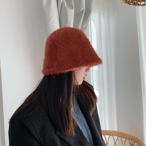 Detail view of a brownish-red plush bucket hat on a model for winter fashion styling