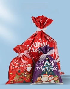 Three sizes of Christmas drawstring gift bags with Santa and reindeer on red glossy surface