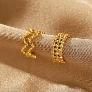 Macro shot of gold beaded texture ear cuff displayed on elegant satin background