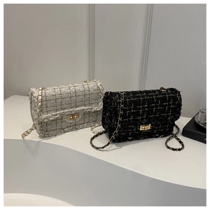 Close-up of black and white tweed crossbody bags with golden chain straps and locks