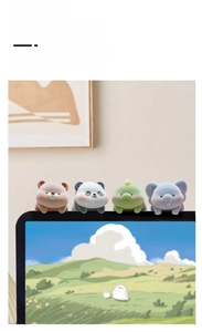 Close-up of fluffy bear, panda, elephant, and dinosaur ornaments on a computer screen edge