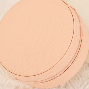 Detail of round pink PU leather jewelry box with zipper and cross-grain texture