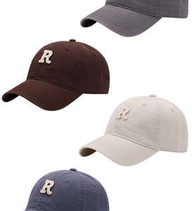 Detailed macro view of four cotton baseball caps with embroidered R letters in different colors