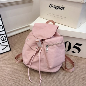 Detail view of pink nylon backpack featuring buckle closure and front zipper pocket