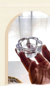 Close-up of a hand holding a transparent glass flower-shaped tea light candle holder