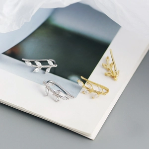 Macro detail of leaf-shaped ear cuffs in silver and gold with sparkling zircon stones