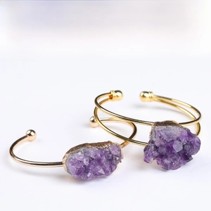 Close-up of raw purple amethyst cluster on a gold plated adjustable open cuff bracelet