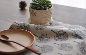 Detail of beige linen napkin with black tree pattern and wood tray decor