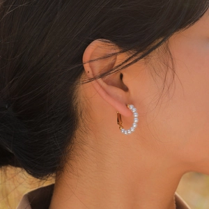 Elegant C-shaped gold-plated stainless steel earrings with white pearls on a model