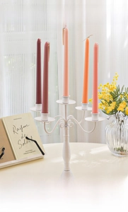 Detail of elegant gradient taper candles in pink and burgundy on a white iron candelabra