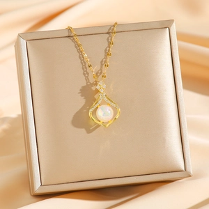 Golden titanium steel necklace with iridescent teardrop pendant on jewelry box