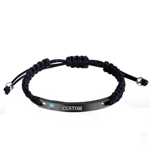 Detail of adjustable braided bracelet with custom engraved metal bar and blue zircon stone