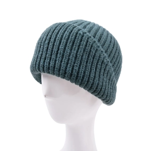 Macro detail of dark green ribbed knit beanie showing thick texture and folded cuff