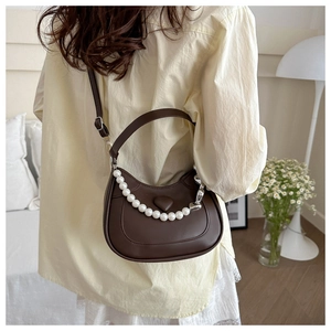 Detail of dark brown crescent bag with pearl chain strap and heart decor shown on model