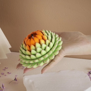 Detailed view of a handmade lotus-shaped candle with gradient petals held in hand