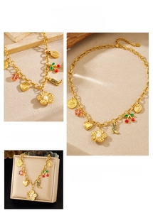 Detail of gold necklace with cherry, pearl flower, heart, and luck coin charms