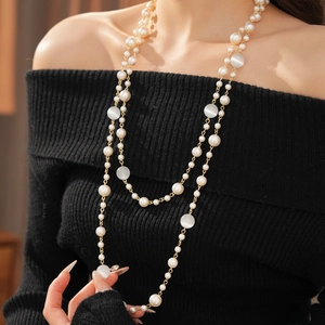 Close-up of layered necklace with white pearls and cat eye stones on a black sweater