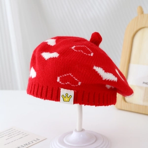 Detail of red knit beret featuring white cloud jacquard and crown logo tag detail
