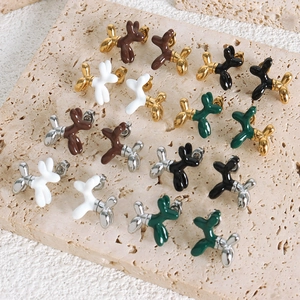 Modern balloon dog stud earrings in colorful enamel finish on travertine display