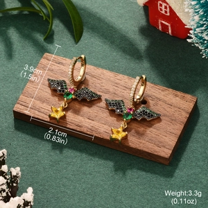 Detail view of gold bat wing earrings with size specs on a festive holiday background