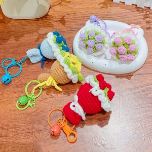 Handmade crochet flower bouquet keychains in various colors on a rustic wooden desk