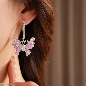 Close-up of pink zircon butterfly hoop earrings worn on a model with soft lighting