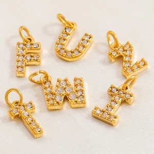 Gold letter charms with cubic zirconia inlay on white satin for DIY jewelry